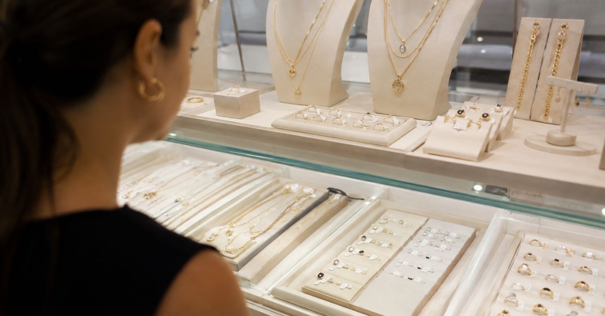 Consumidora observa joias expostas em vitrine de loja durante período de compras para o Dia das Mães.