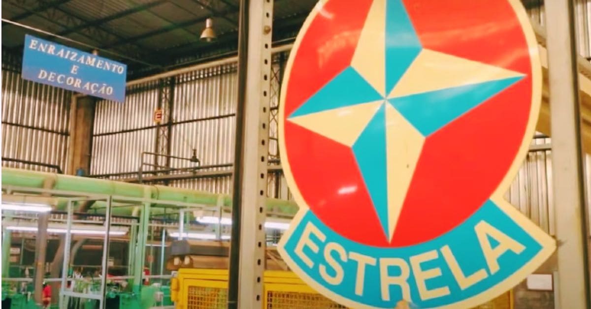 Fachada interna de fábrica da Estrela durante período de recuperação judicial, com logotipo da empresa em destaque diante da área industrial.