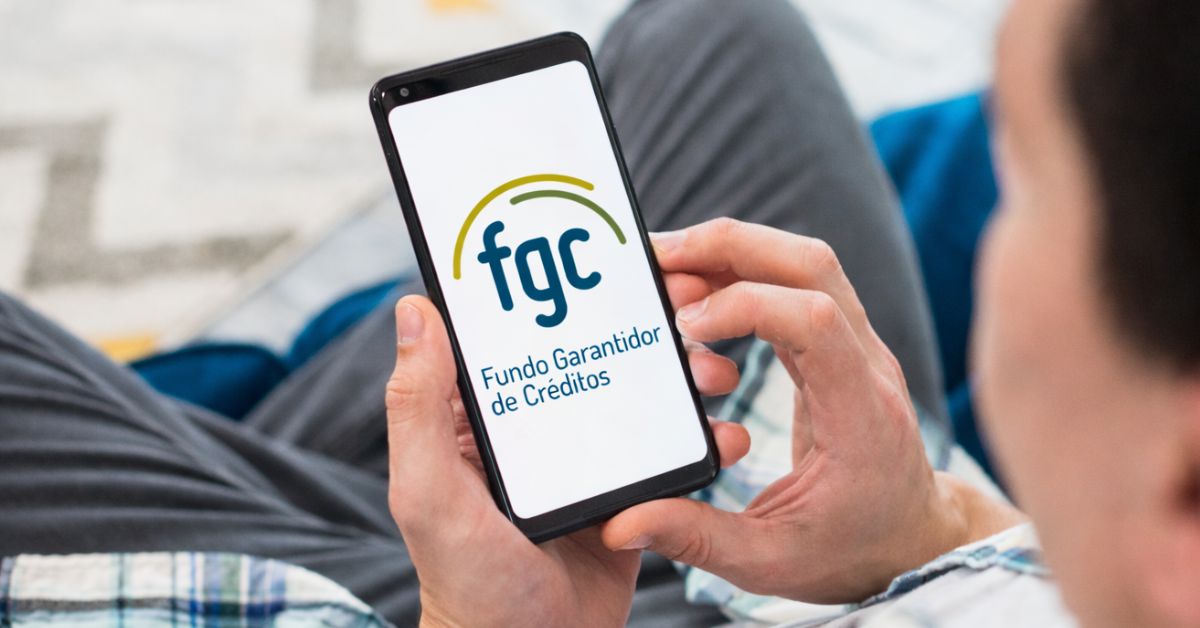 Pessoa segura um smartphone exibindo o logotipo do Fundo Garantidor de Créditos (FGC), entidade responsável por proteger depósitos e aplicações financeiras dentro dos limites estabelecidos pela regulamentação brasileira.