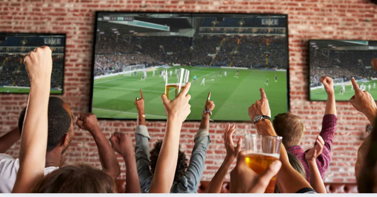 Clientes assistem a partida de futebol em telões de bar durante transmissão de jogos da Copa do Mundo 2026.