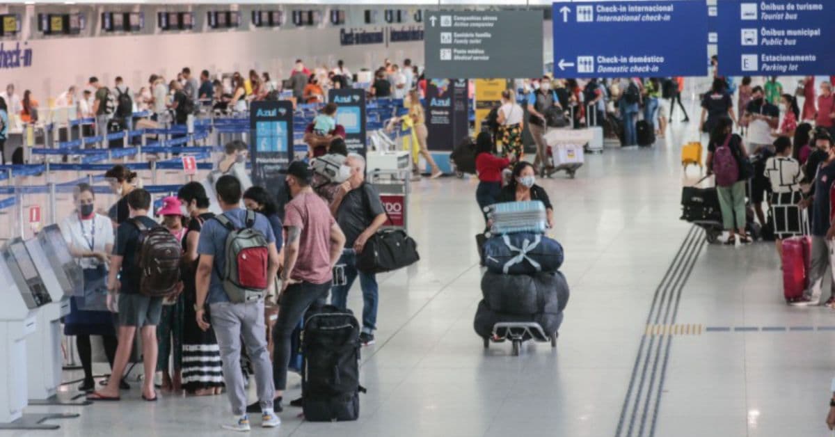 Passageiros na área de check-in de um aeroporto brasileiro durante movimentação de voos nacionais e internacionais.