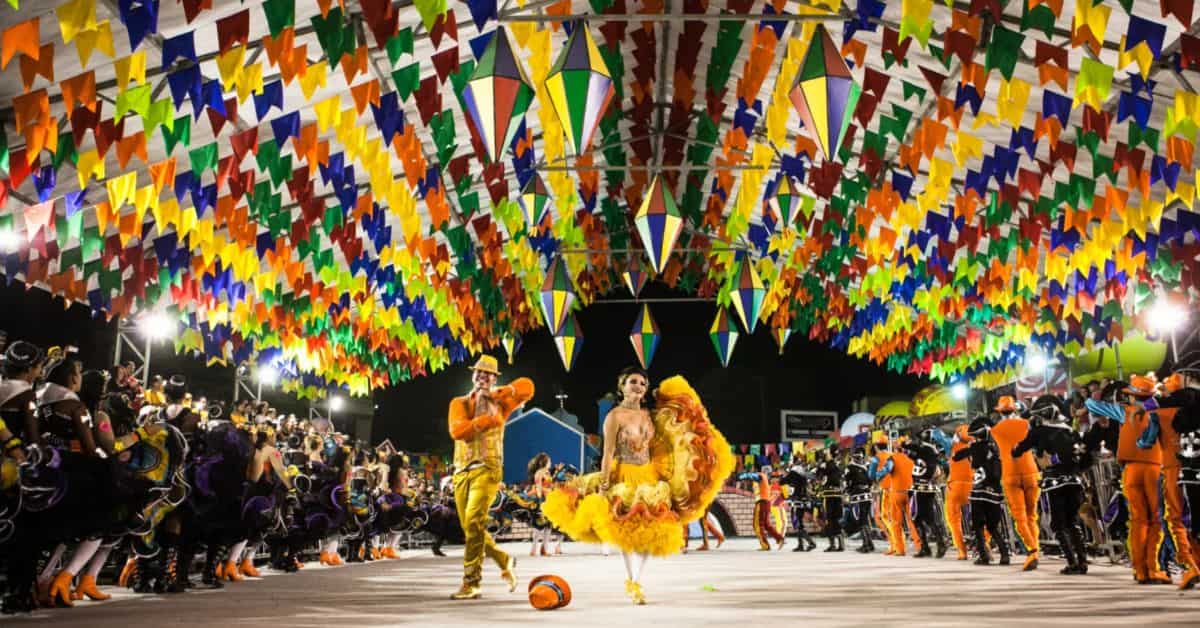 Quadrilha junina se apresenta sob bandeirolas coloridas durante festa de São João, evento que movimenta turismo, comércio e serviços no Nordeste.