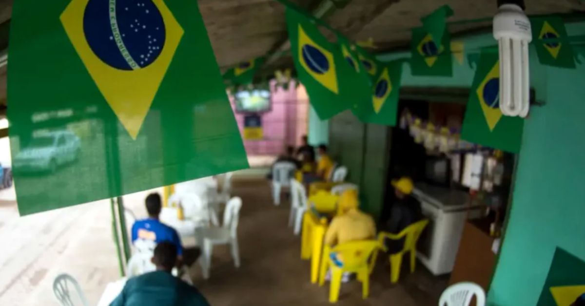 Bandeiras do Brasil decoram um bar enquanto clientes acompanham o clima de expectativa para os jogos do Brasil no horário de trabalho durante a Copa de 2026.