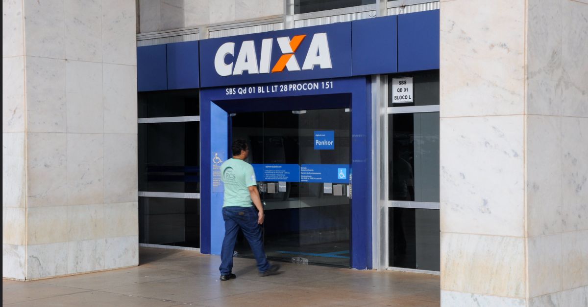 Fachada de uma agência da Caixa Econômica Federal, com cliente entrando na unidade, em imagem que ilustra a discussão sobre a reestruturação administrativa do banco.