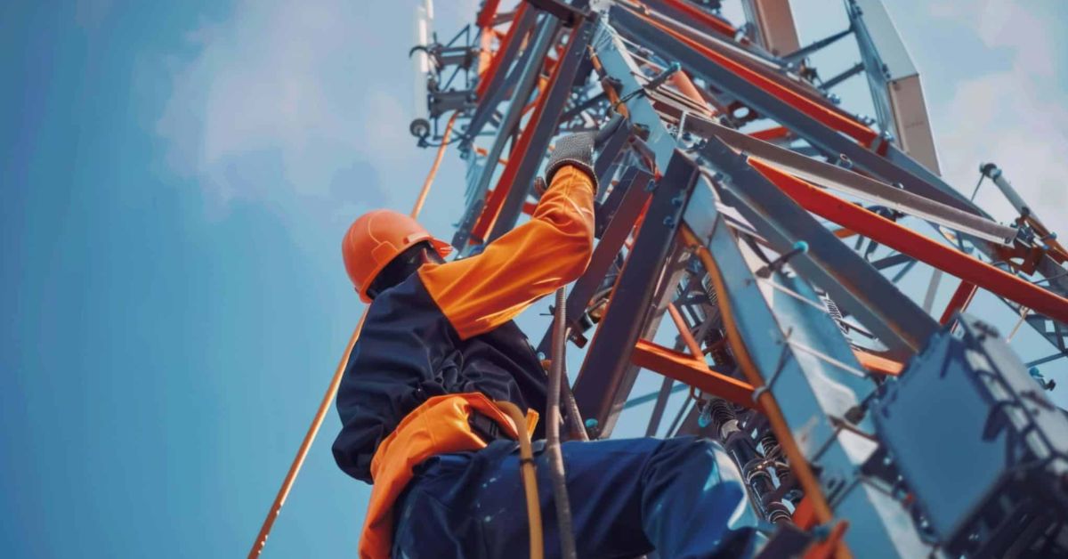 Setor de serviços no Brasil: técnico realiza manutenção em torre de telecomunicações ao ar livre.