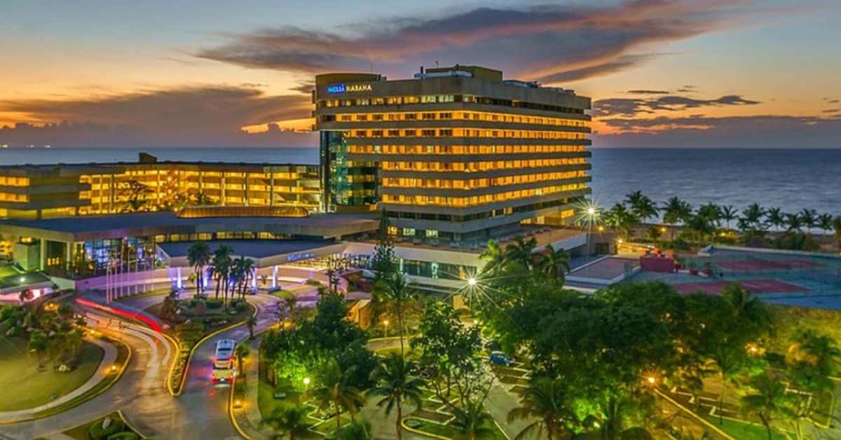 Hotel operado pela Meliá em Cuba iluminado ao entardecer, com vista para o litoral e área turística da ilha.