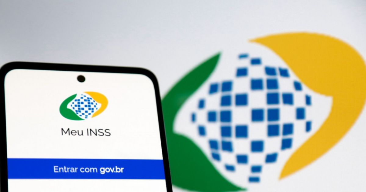 Aplicativo Meu INSS exibido na tela de um smartphone, com a identidade visual do instituto ao fundo, em imagem relacionada aos serviços digitais da Previdência Social.