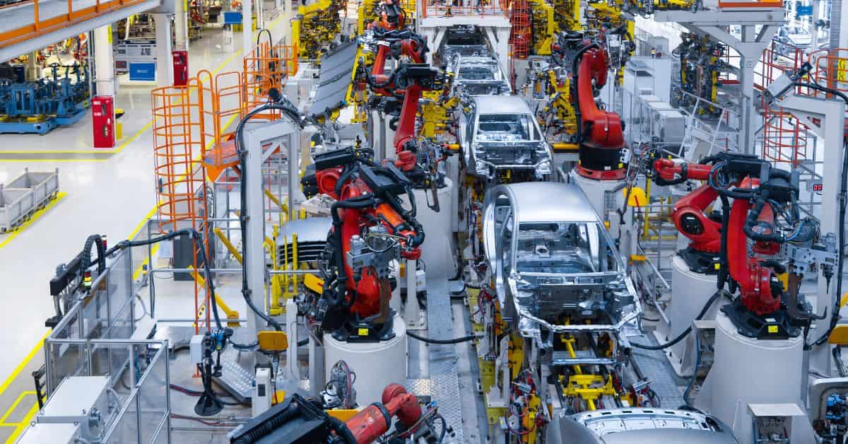 Linha de montagem automatizada da indústria automotiva com robôs industriais durante a fabricação de veículos.